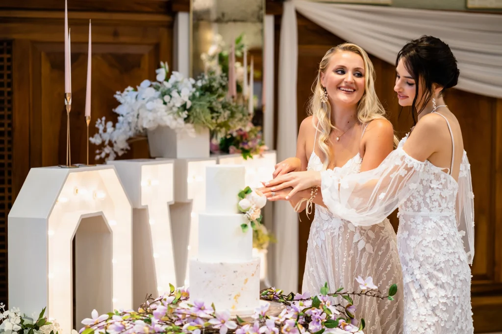 Brides cutting the wedding cake surrounded by floral decor at Pelham House