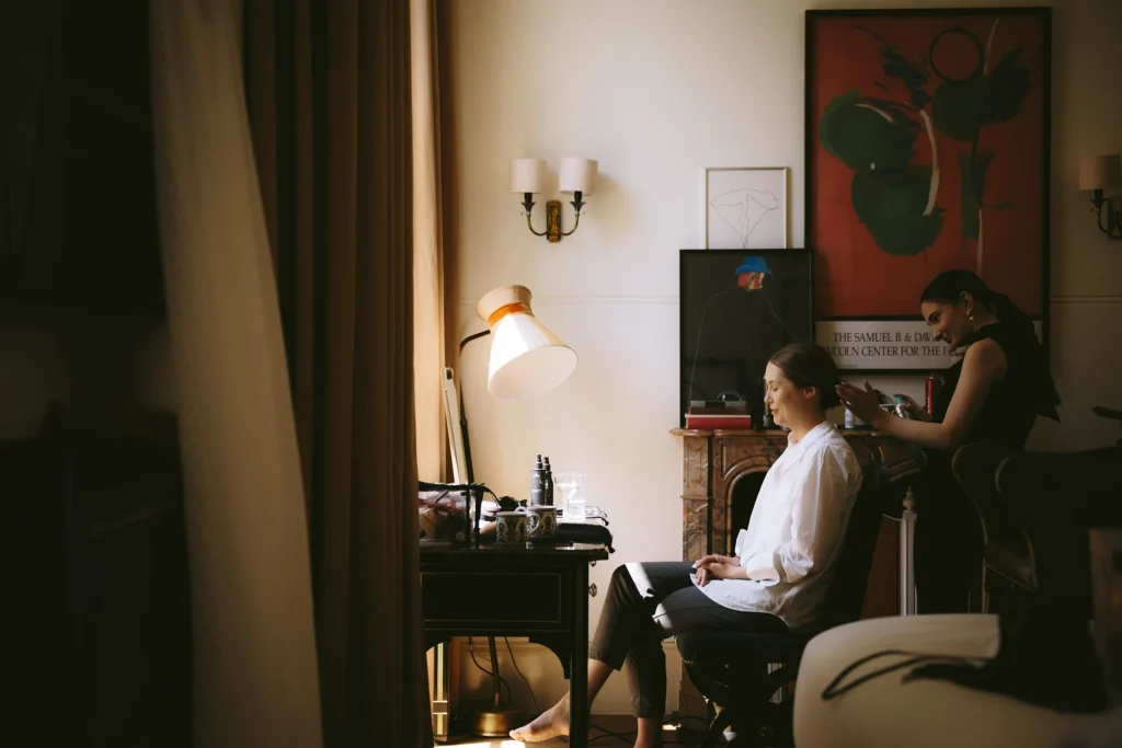 Bride getting her hair styled in a cozy NoMad London suite for a minimalist wedding.