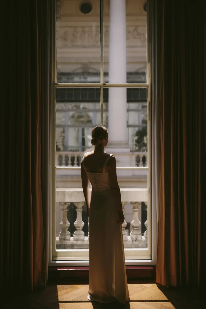 Bride standing by a grand window in NoMad London – perfect for minimalist wedding inspiration.