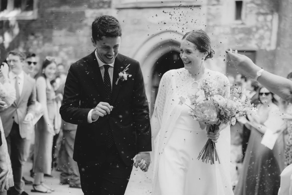 The newlyweds smiling as guests throw confetti outside their minimalist London wedding.