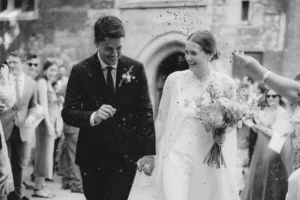 The newlyweds smiling as guests throw confetti outside their minimalist London wedding.