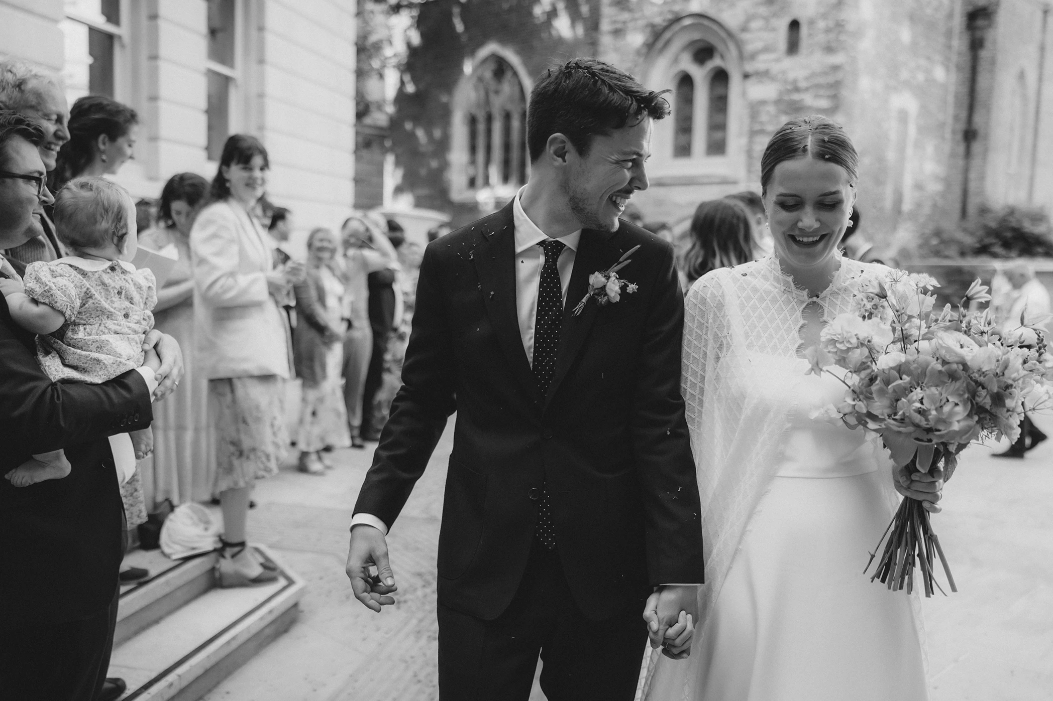 Newlywed couple holding hands and smiling during their outdoor minimalist wedding in London.