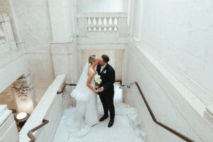 Bride and groom sharing a kiss on the grand marble staircase of a city wedding venue