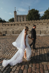 Elegant bride and groom walking along cobbled streets near Tower of London