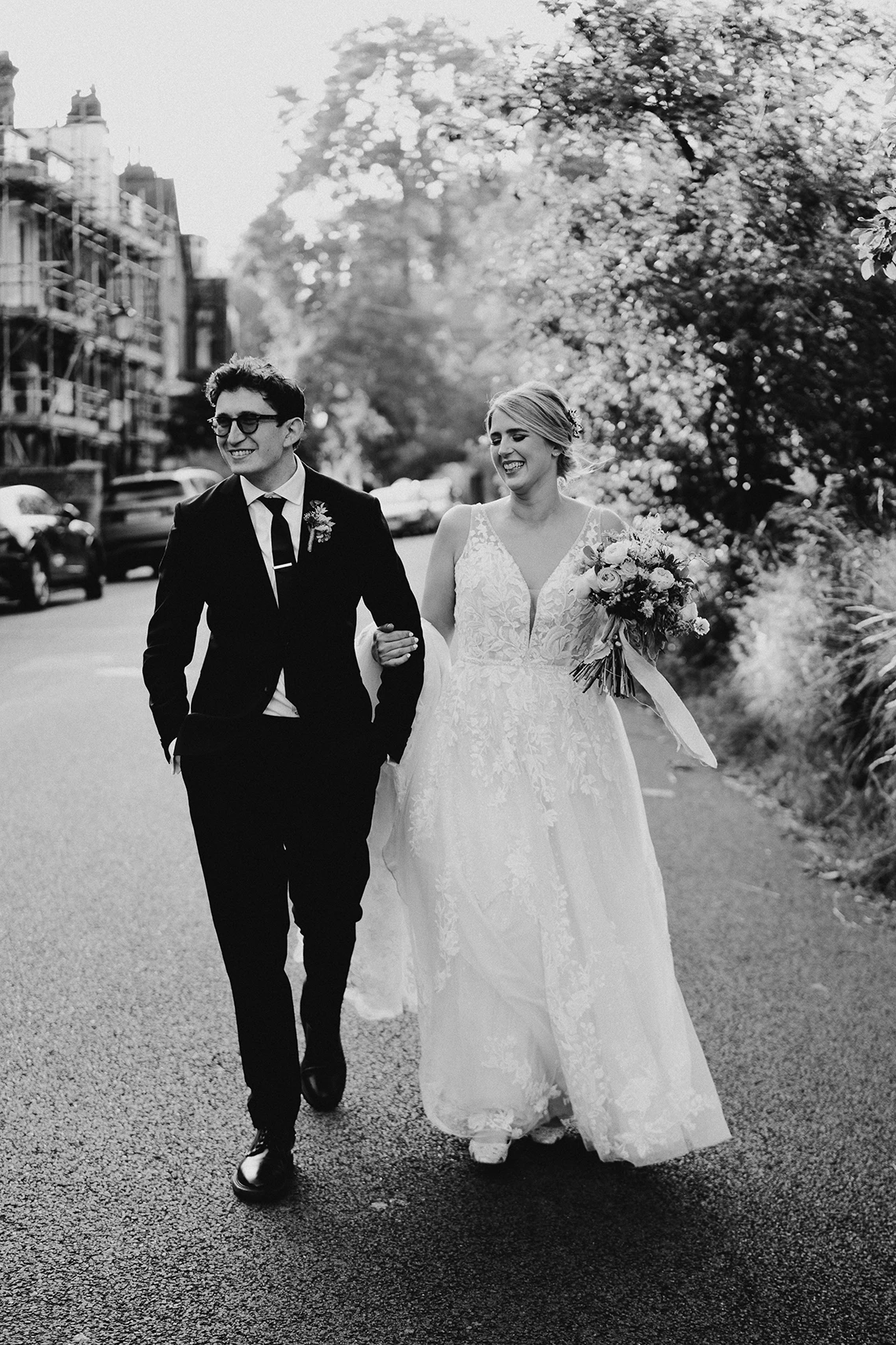 Candid black-and-white photo of a bride and groom walking happily together