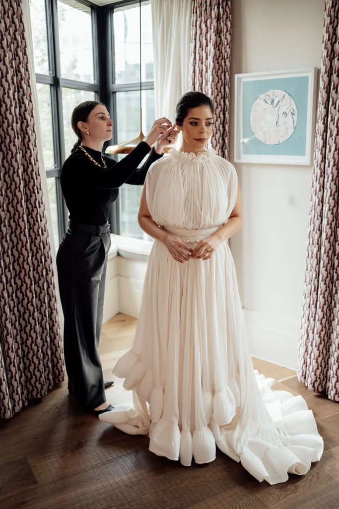 Hairstylist adding the finishing touches to the bride’s elegant updo in preparation for the wedding ceremony