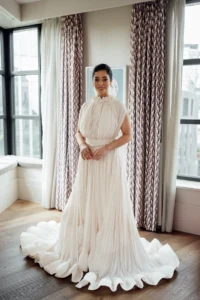 Elegant bride in a pleated wedding gown in a modern suite