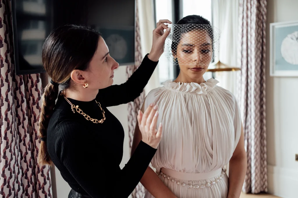 Bride having a delicate birdcage veil adjusted before wedding