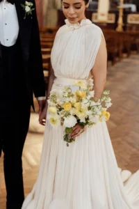 Bride holding a delicate bouquet of yellow and white flowers at her elegant wedding