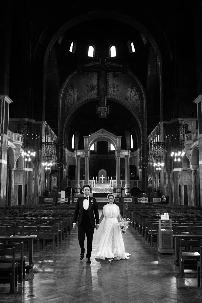 Newlyweds walking hand in hand down the grand aisle of a historic cathedral