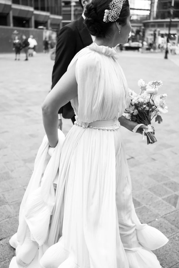 Bride walking through the city streets, holding her elegant wedding dress