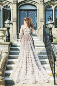 Bride in a luxurious ruffled gown walking up castle steps