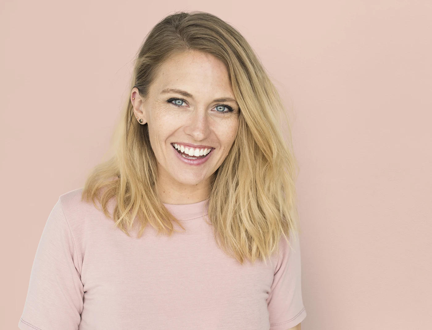 Smiling woman with natural beauty look against a soft pink background