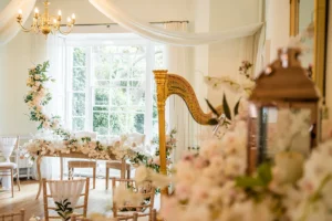 Elegant wedding ceremony setup with floral decor and a golden harp