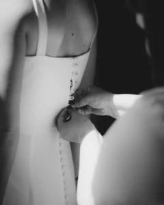 Close-up of a bride’s wedding dress being buttoned up before her makeup trial