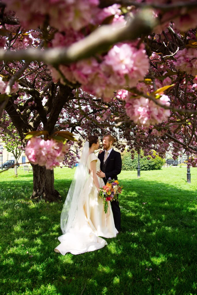 Newlyweds embracing under cherry blossoms