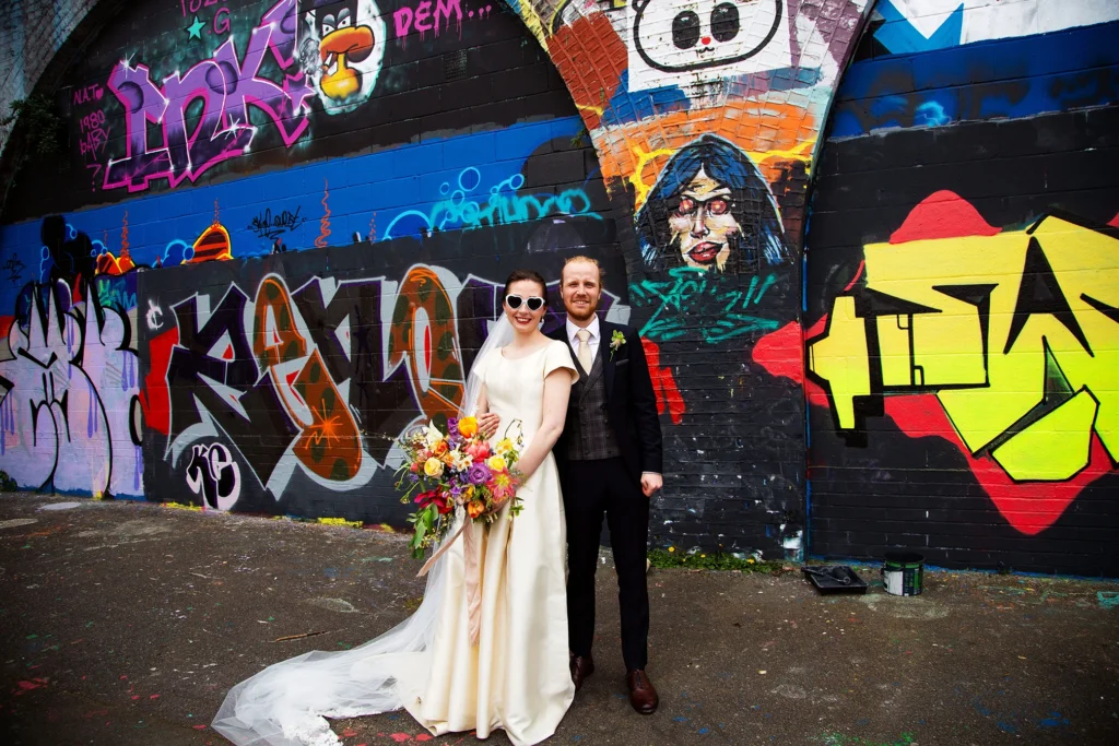 Bride and groom posing in front of a graffiti wall