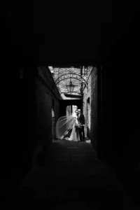 Bride and groom standing under an arched alley in London