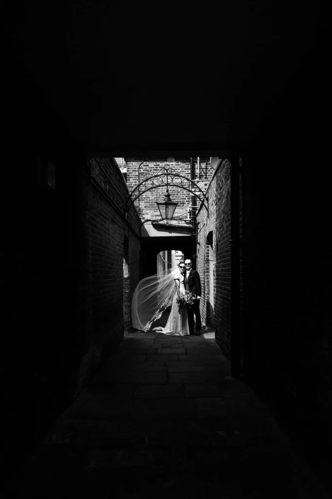 Bride and groom standing under an arched alley in London