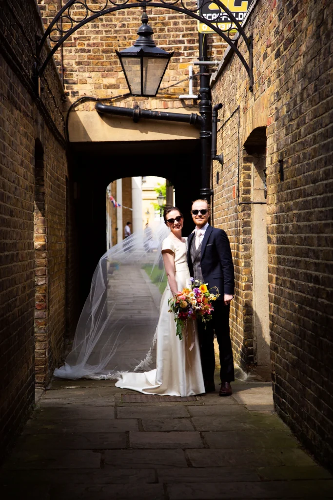 Newlyweds posing in a charming brick alley after their Asylum Chapel wedding