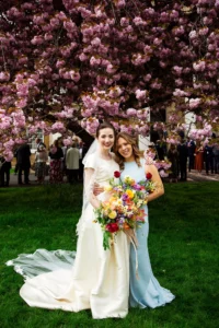 Bride posing under cherry blossoms with a bridesmaid