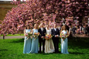 Bride, groom, bridesmaids, and groomsmen posing under cherry blossoms