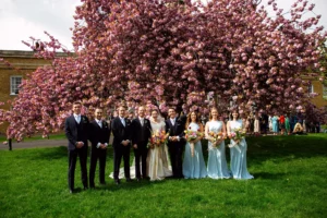 Full wedding party posing in front of cherry blossoms