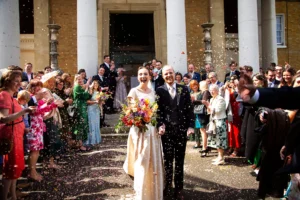 Bride and groom walking out of Asylum Chapel as guests throw confetti