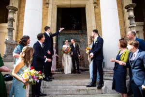Bride and groom holding hands as wedding guests celebrate with confetti