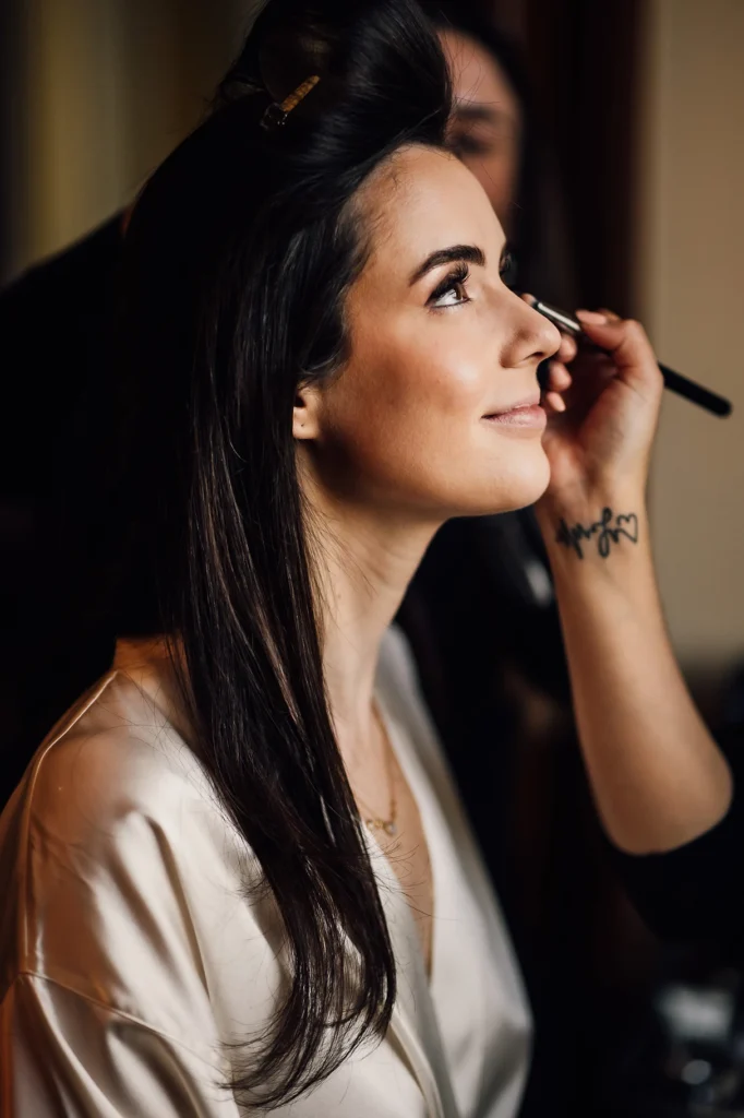 Bride getting makeup applied in soft lighting