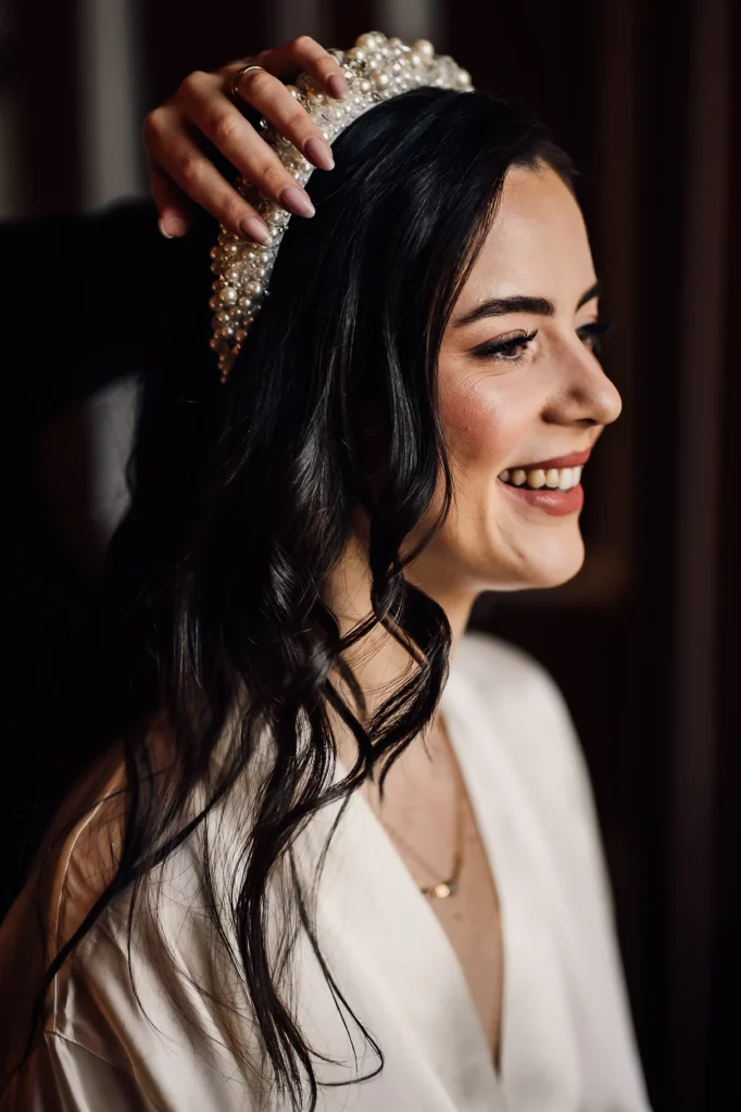 Bride smiling as hair accessory is placed before wedding ceremony