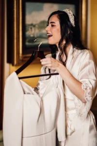 Bride smiling while holding her wedding dress on a hanger