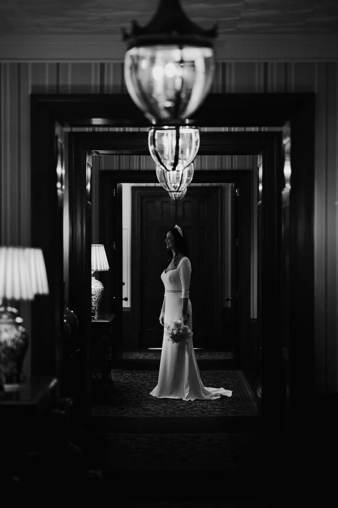 Black and white image of bride standing in a grand hallway