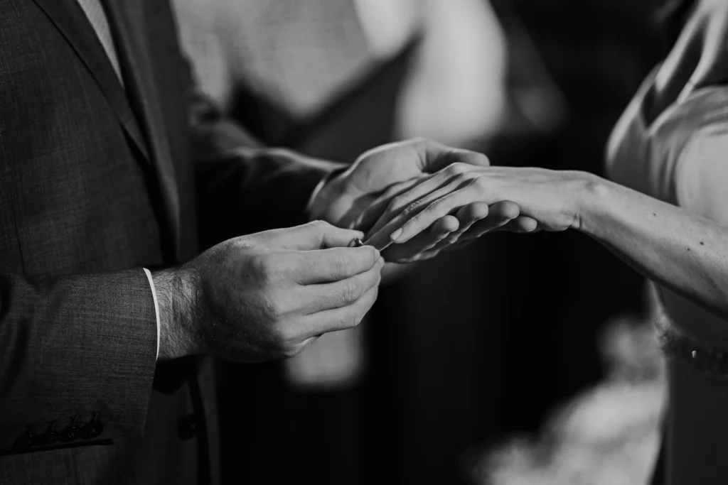 Groom placing wedding ring on bride's finger during ceremony