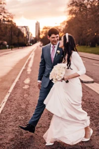 Bride and groom laughing together while walking in the street at sunset