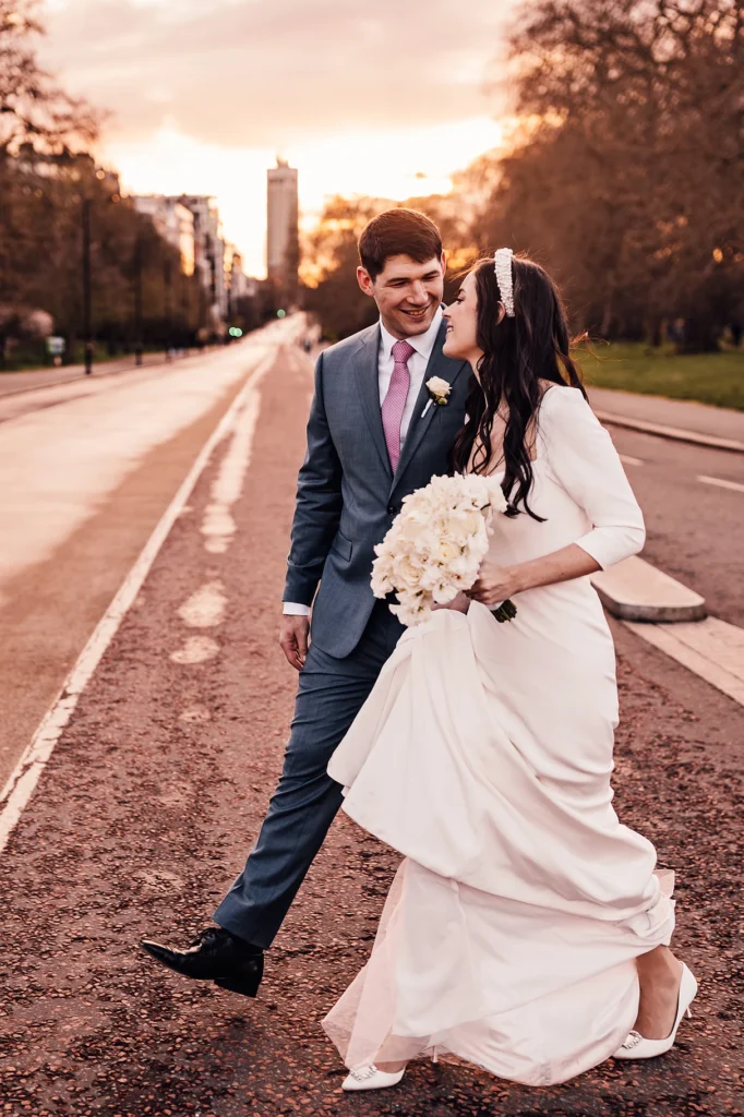 Bride and groom laughing together while walking in the street at sunset