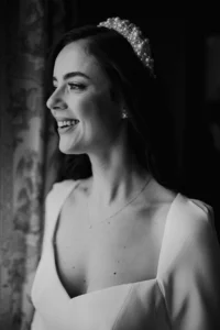 Bride smiling by the window, wearing pearl headband