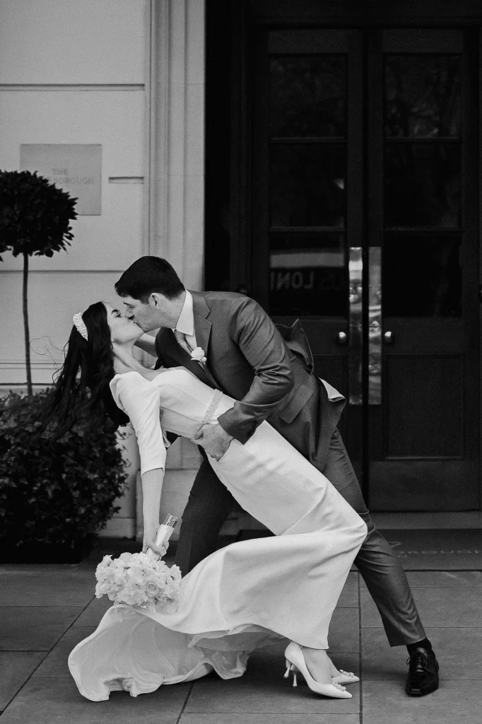 Groom dipping bride in a romantic kiss outside The Lanesborough