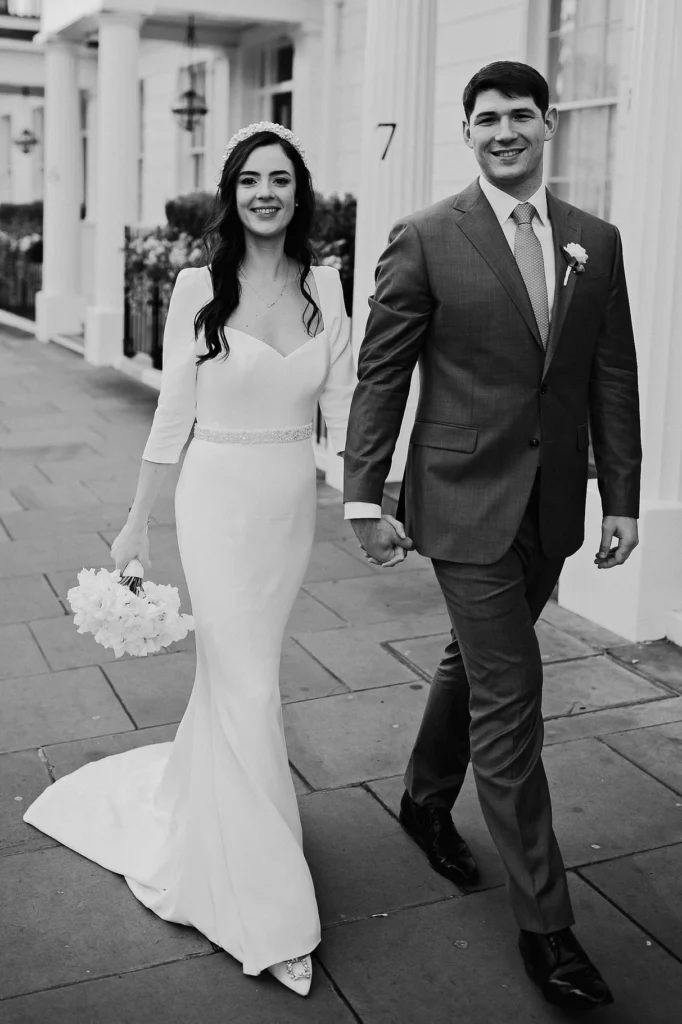 Bride and groom smiling during a walk, captured in black and white
