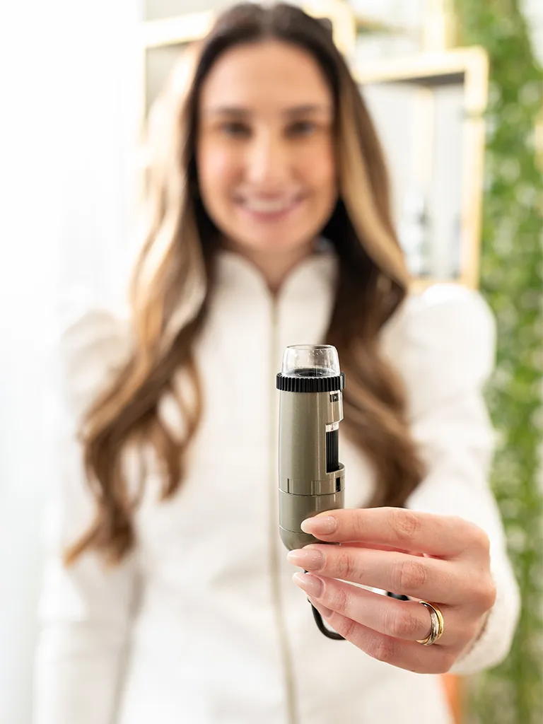 Trichologist holding a digital trichoscope for scalp analysis at Izabella Bordignon London.