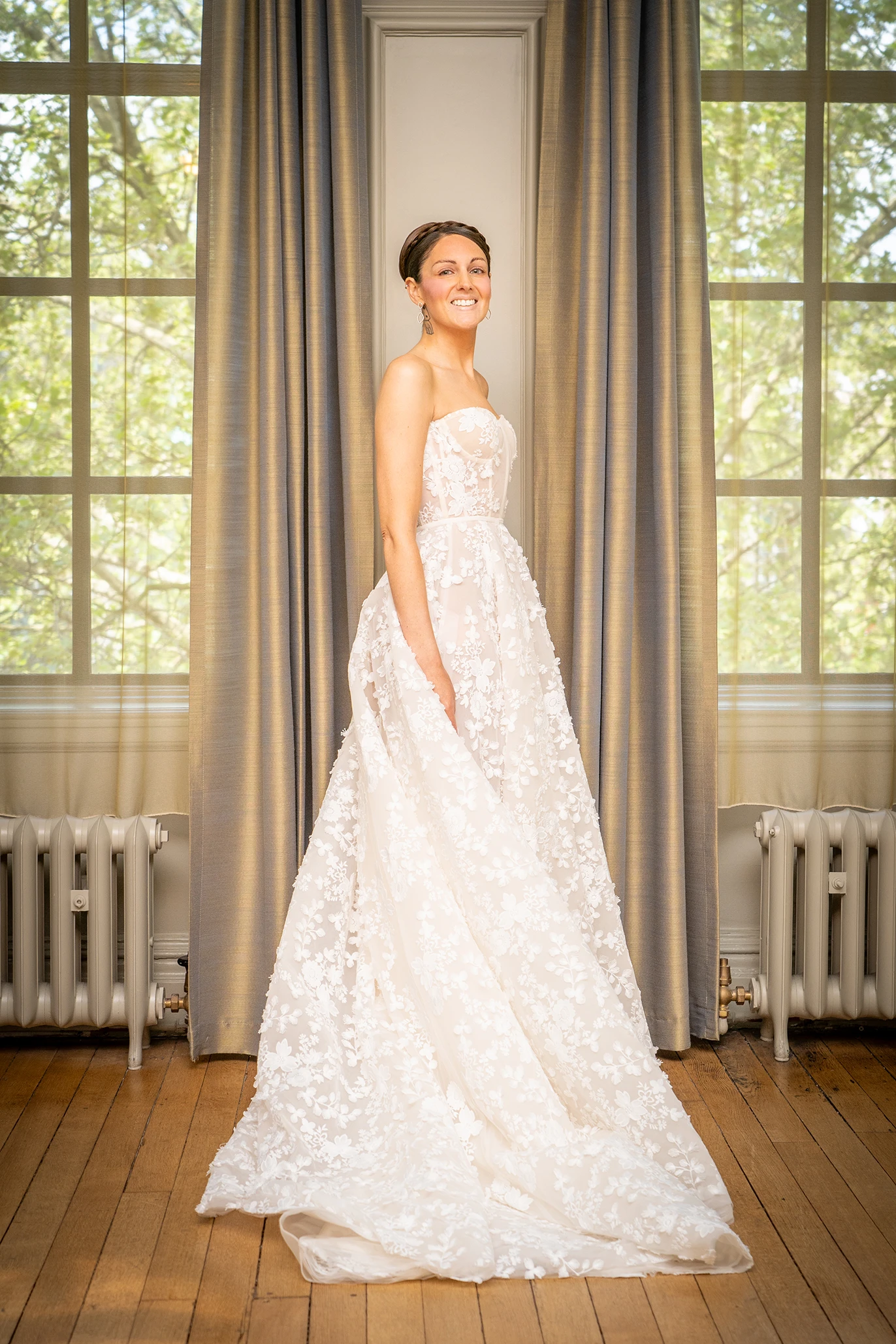 Bride standing elegantly in front of large windows