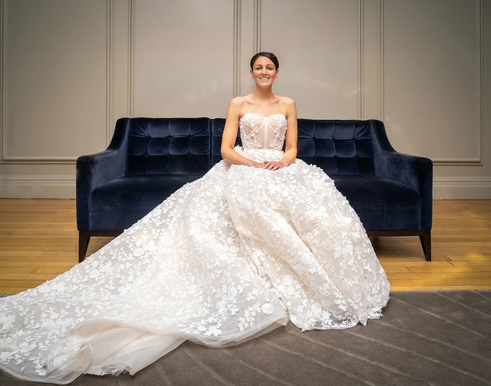 Bride sitting on a navy sofa with flowing wedding dress