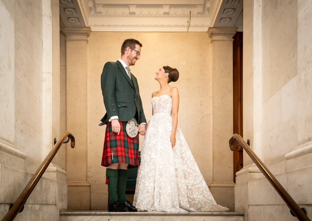Bride and groom holding hands on marble staircase