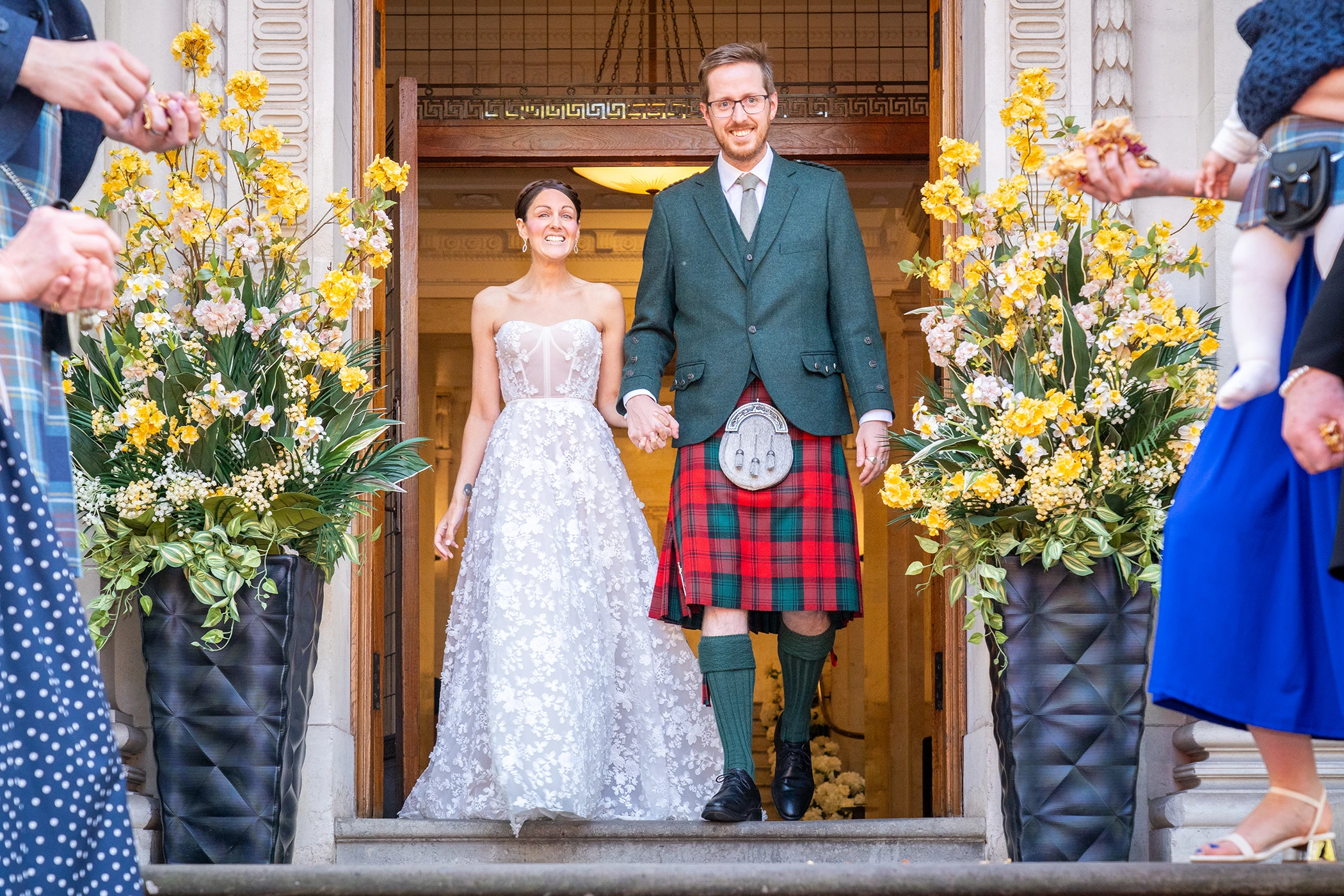 Bride and groom walking out past flower arrangements