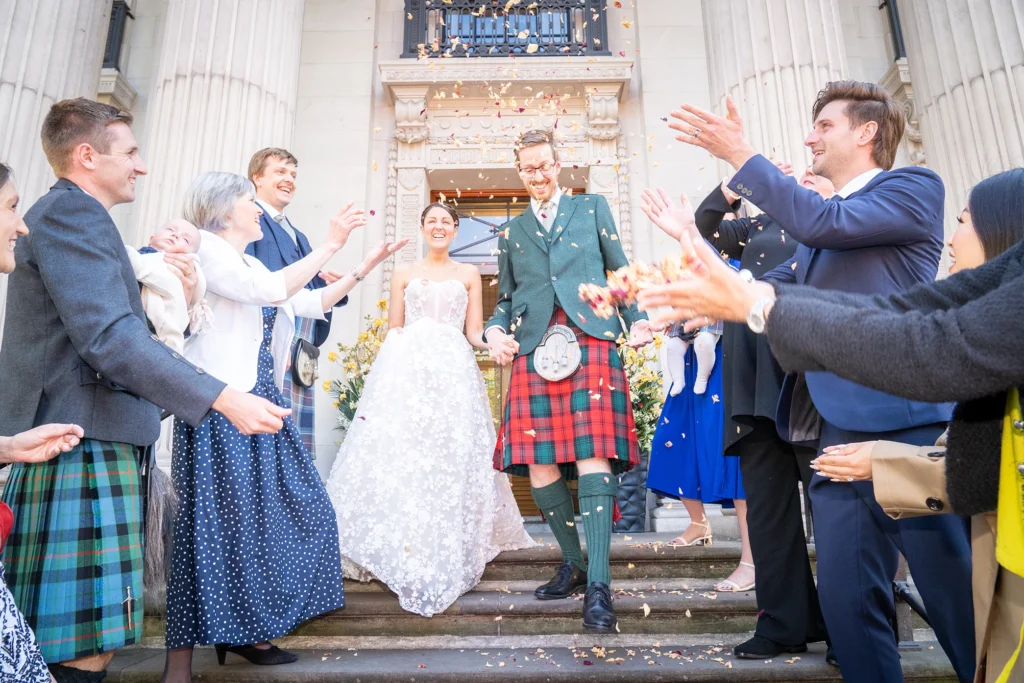 Wedding guests throw confetti at couple
