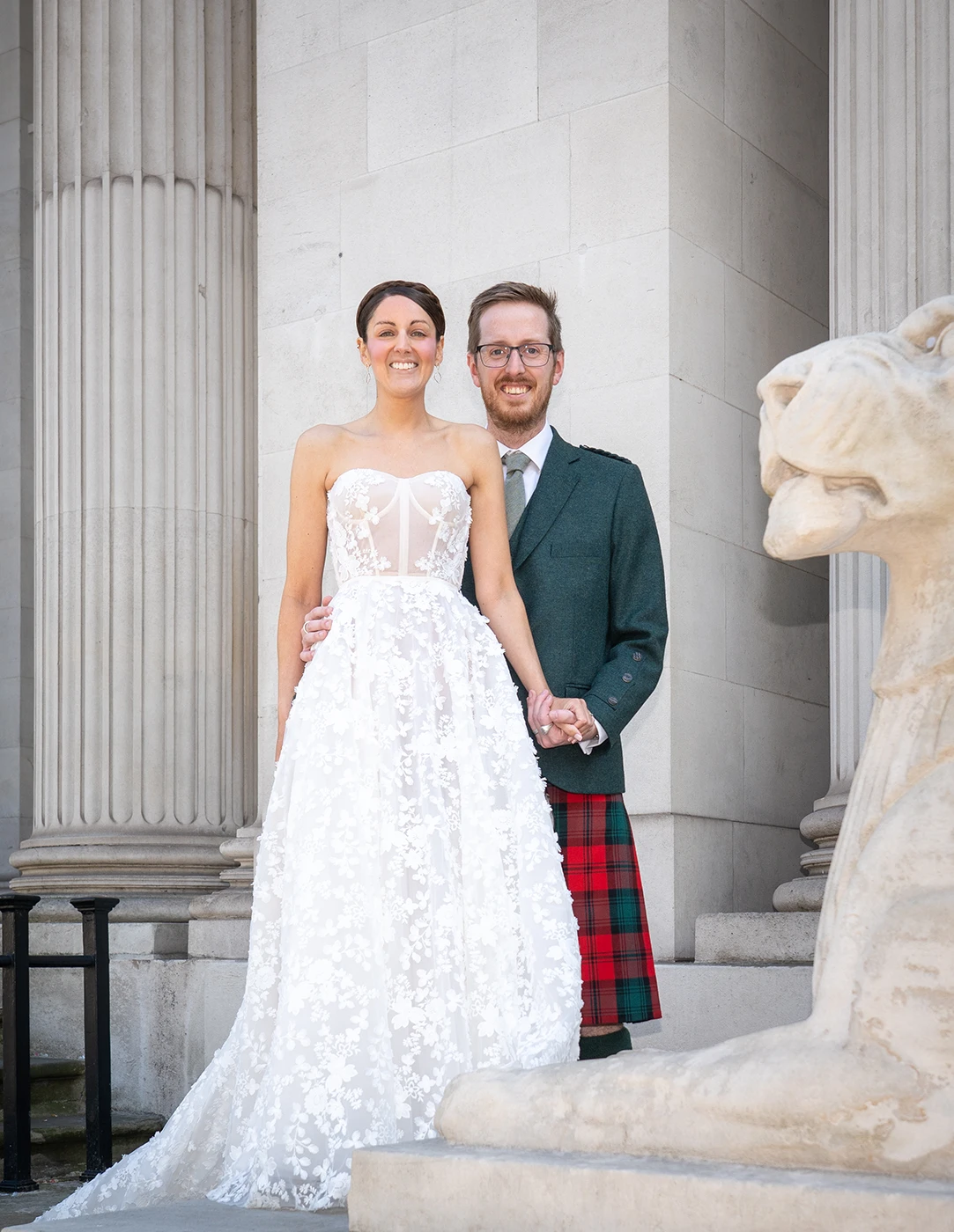 Bride and groom posing near stone lion