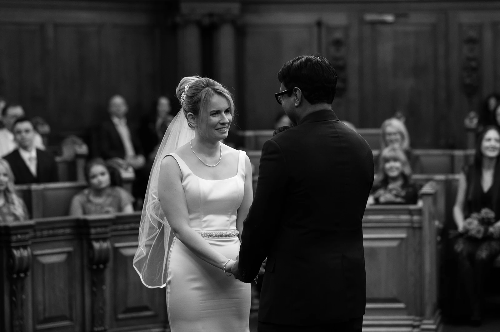 Bride and groom holding hands during wedding vows in ceremony room