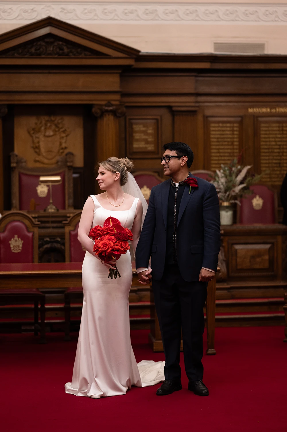 Newly married couple standing together in wedding ceremony room holding bouquet