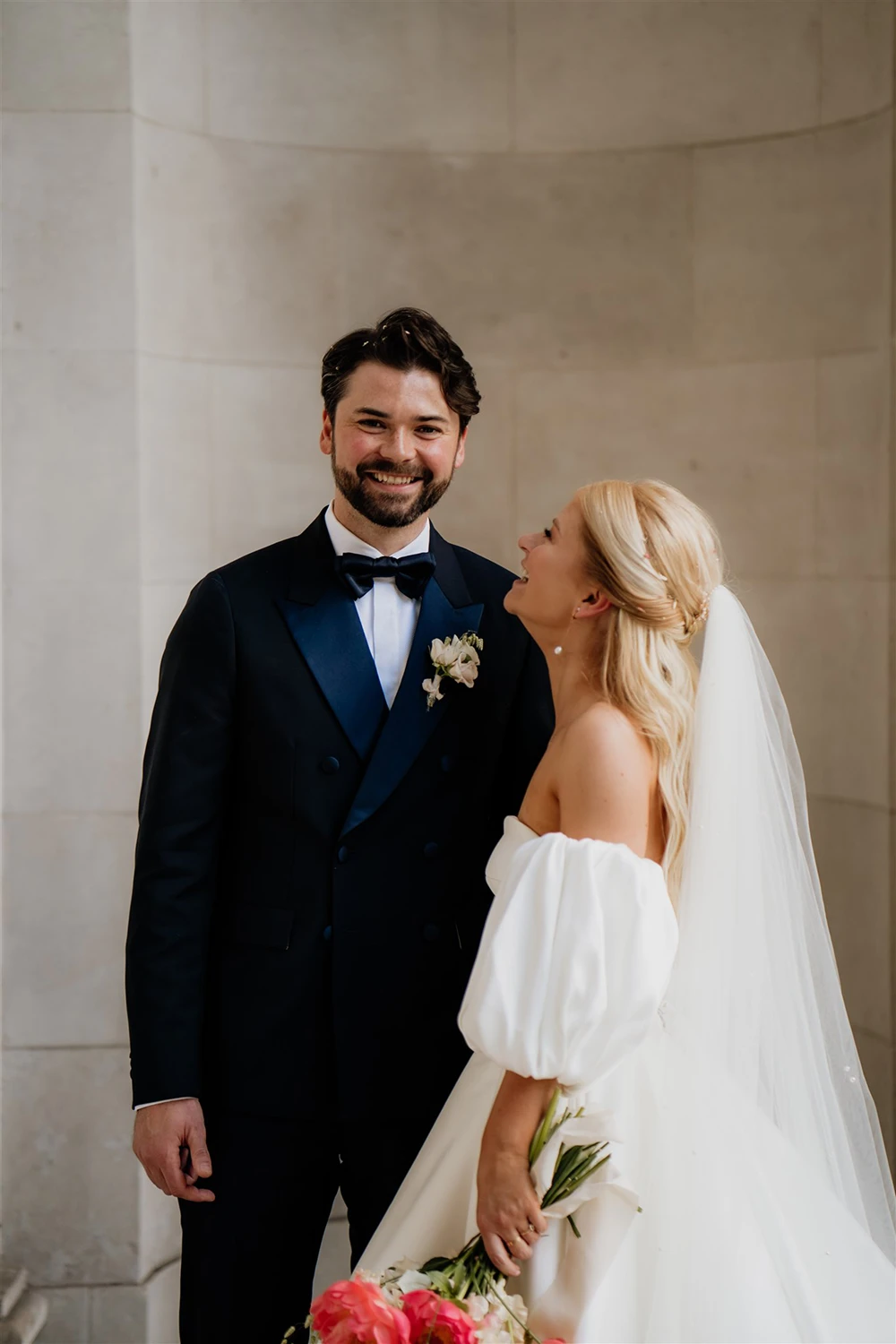 Bride looking up and smiling at groom during a relaxed wedding portrait.