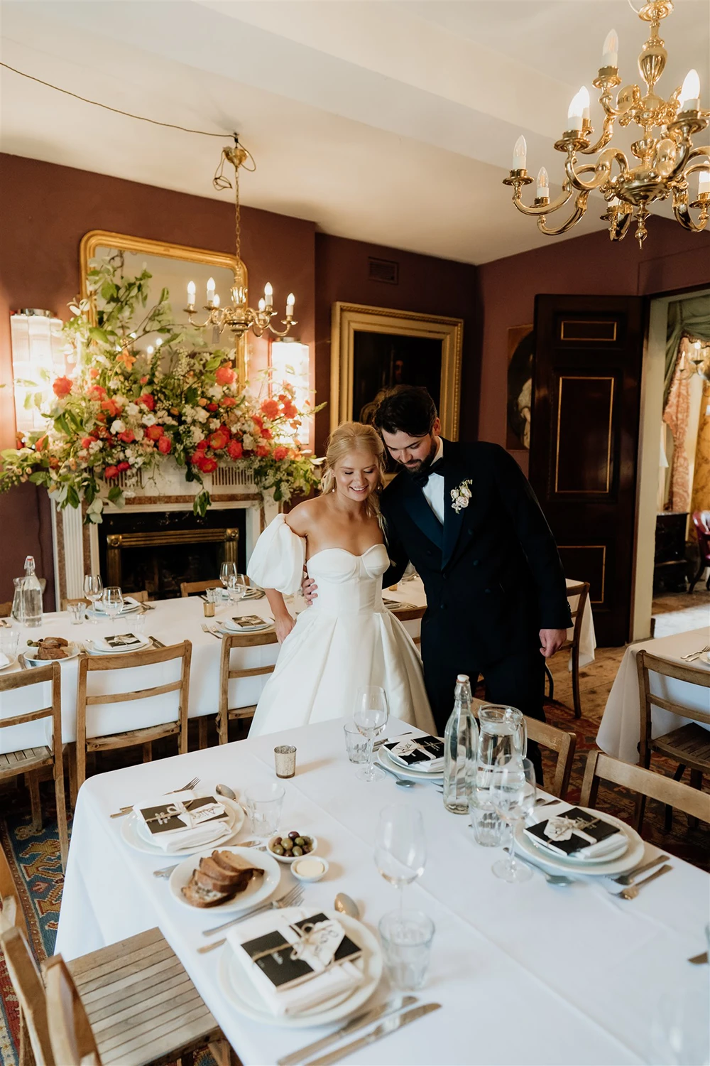 Bride and groom standing together beside a long wedding reception table set with plates, glasses and candles at Brunswick House Wedding